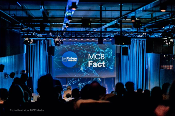Bilde av en konferansesal med MCB Fact bilde på lerretet i salen
