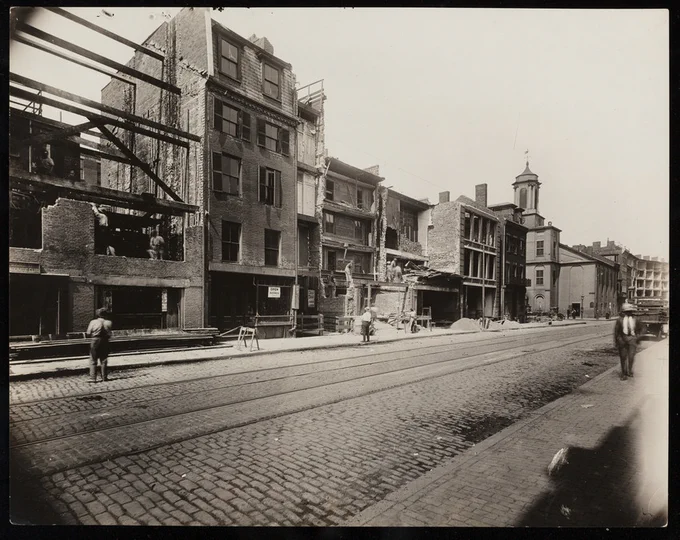 Photo taken in 1920 of half demolished brick buildings along Charles Street during street widening. 
