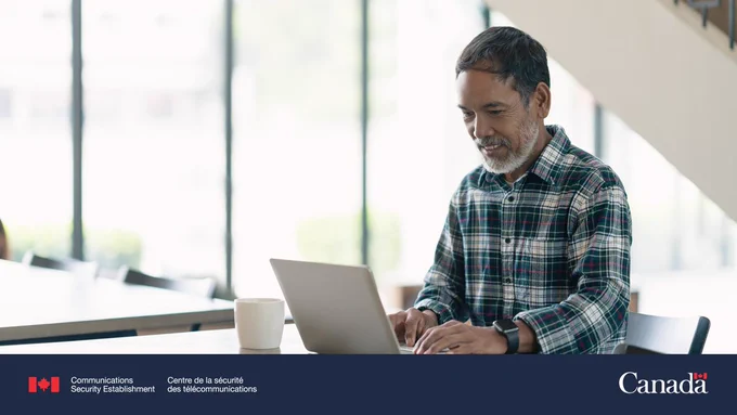 A person sits at a table and works on their laptop.