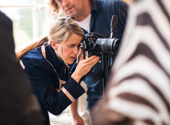 Natalie Lennard squints behind a camera on a professional photoshoot.