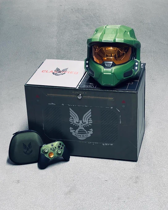 Ein Master Chief Helm auf einer Box. Davor eine Xbox elite wireless Controller Series 2 - Halo Infinite Limited Edition.