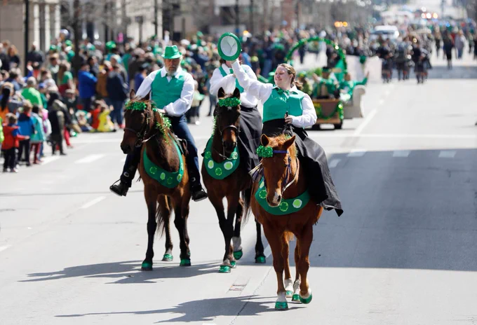 horses and riders dressed in green walking in a parade