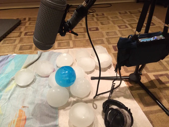 A recorder and microphone set up to record a pile of head-sized solid balls of ice, one of them dyed blue