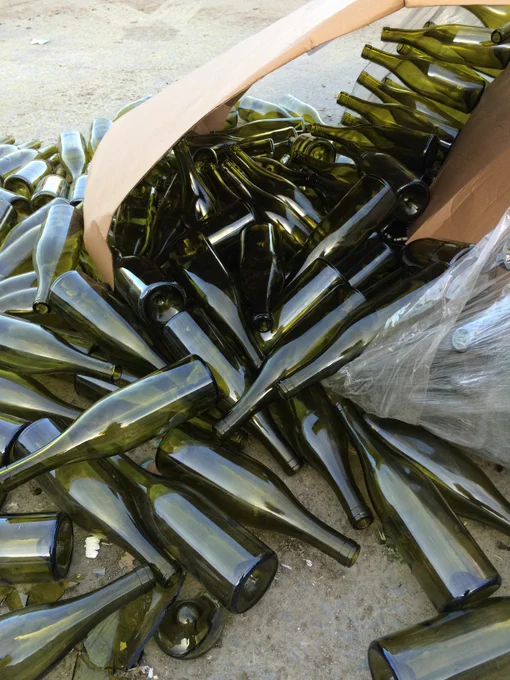 A spilled-out box of hundreds of perfect wine bottles at a recycling depot