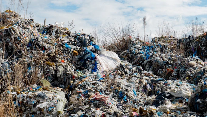 Piles of disorderly waste, consisting of plastic and other materials, in a grassy field