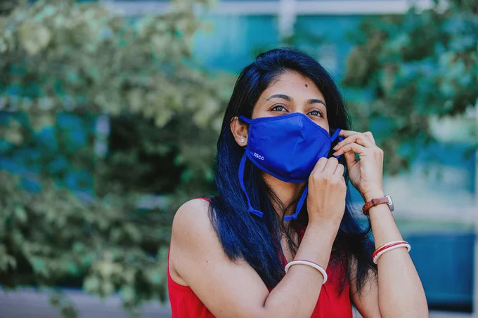 A woman adjusts her protective face mask while standing outside an NSCC campus.