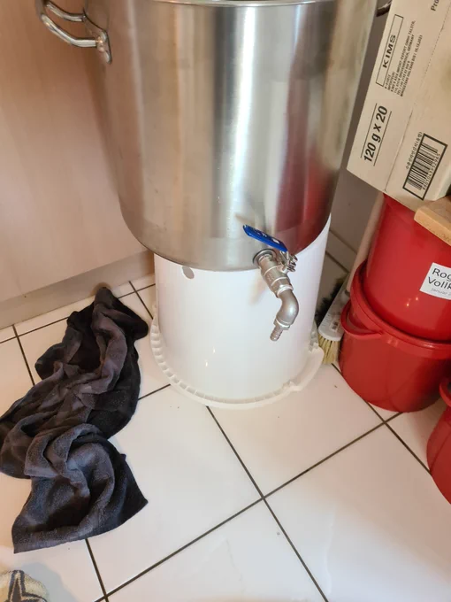 Ein Topf auf einem umgedrehten Eimer. Auf dem Boden darum liegen zwei durchnässte Frotteetücher
