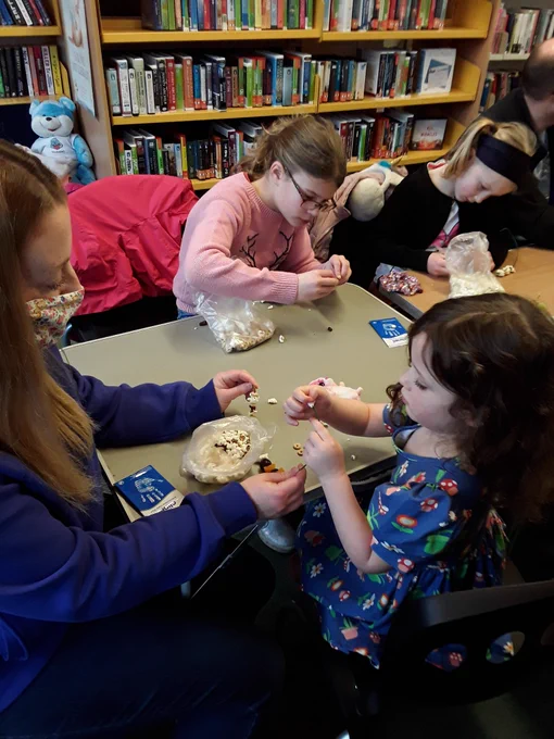 A child and adult make a bird feeder with  popcorn