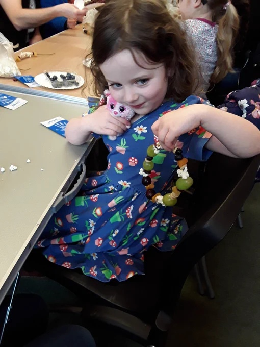A child holds up her completed bird feeder