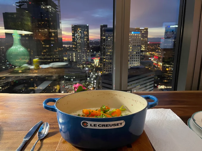 Blue casserole pot with veal casserole buildings in background and sunset