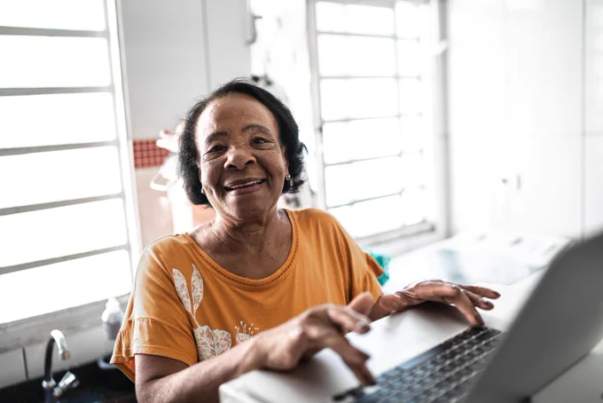 Stock photography of an elderly black woman working on a laptop computer. 