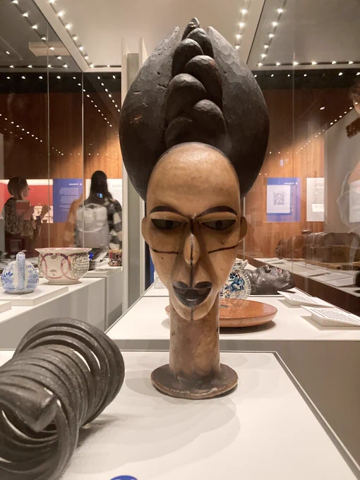 A wooden sculpture of a woman's head with prominent hair