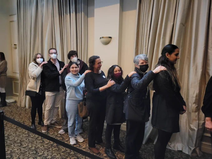 Excited participants are ready to be escorted to their table where they will dine in the dark with Lighthouse of Big Bend.  They are lined up with their hand on the shoulder of the person in front of them as a modified human guide technique