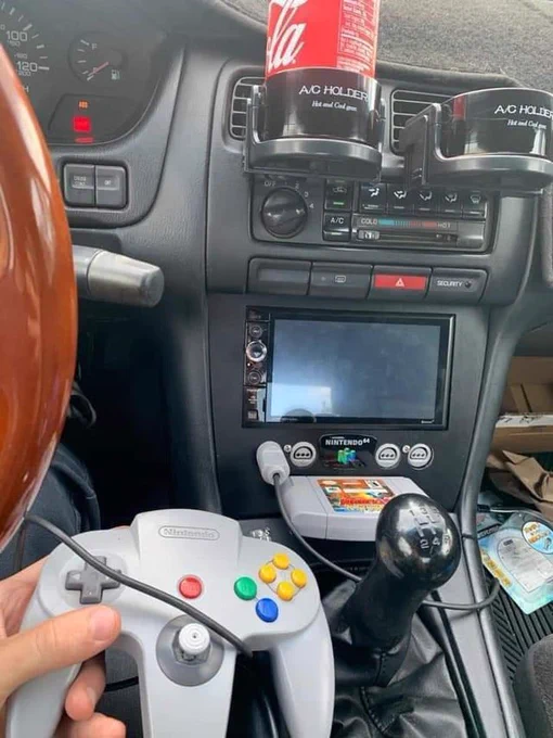 Photo of a Nintendo 64 modded into a car console where the radio and screen should be, with a cartridge and controller plugged in