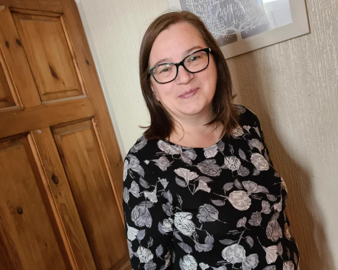 Karen is smiling to camera after being on the low calorie diet programme for around a year. Karen is wearing a black top with a white flowery pattern.
