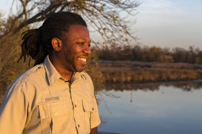Photo description: Lamar Gore, Refuge Manager at John Heinz National Wildlife Refuge At Tinicum in Philadelphia, looking at the horizon, wetland or river in the background at John Heinz National Wildlife Refuge by Ian Shive/USFWS