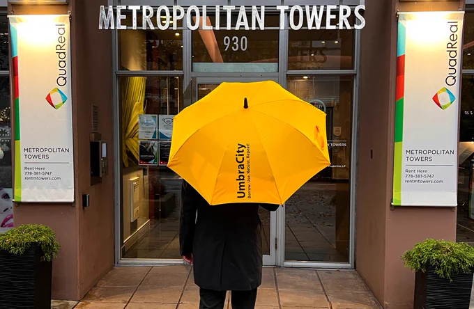 person standing outside of building with yellow umbrella