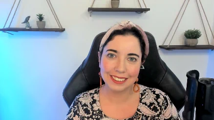 A picture of Anna sitting at her desk with a microphone and blue lighting behind her
