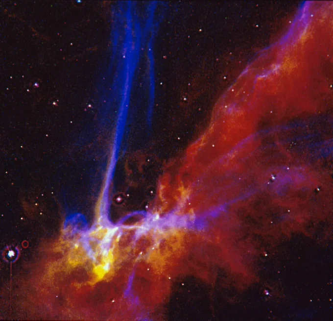 Supernova filament which looks like red and blue gases. From the bottom left shoots up a blue column of light, which is actually heated gas. The supernova remnant looks like a reddish, irregular cloud of smoke. 