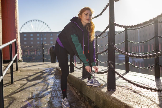 girl tieing trainers on wall in royal albert dock in daylight