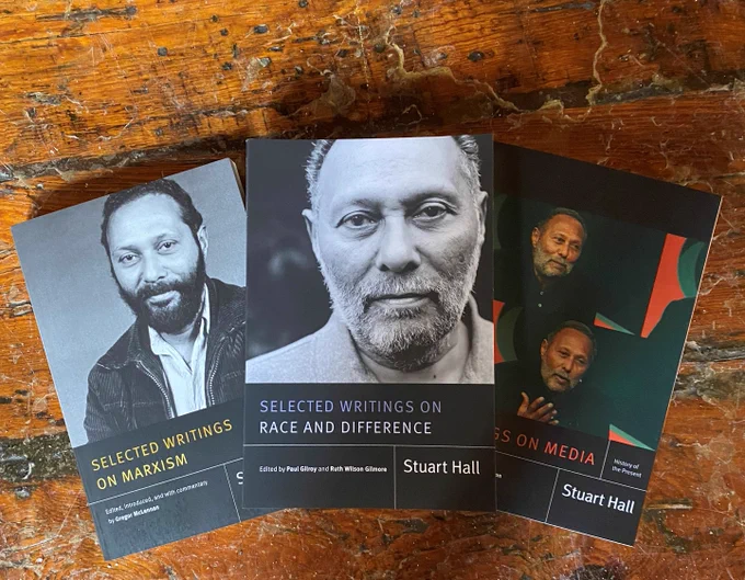 Three books spread out on a wood background. Titles are Selected Writings on Marxism, Selected Writings on Race and Difference and Writings on Media. Stuart Hall's image is on all three.