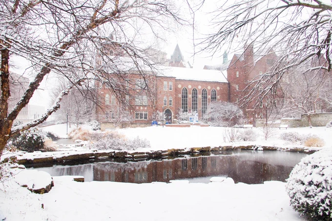 Snow falls on the pond outside of Cook Hall, home of the Chaifetz School of Business
