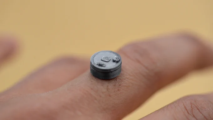 Macro shot: the 3D printed parts stacked atop a ring finger.