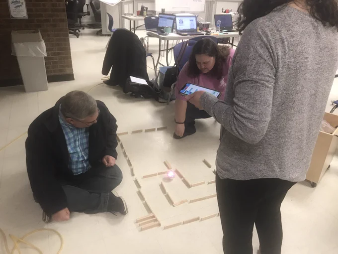 Three teachers code a Sphero robot to navigate a Keva plank maze.
