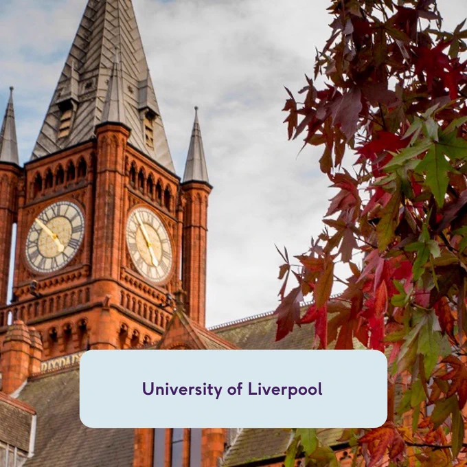 Image shows the clock tower of the Victoria building at University of Liverpool. There are red and green leaves in the right-hand side of the picture.