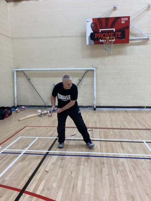 Man with a cricket bat in a sports hall