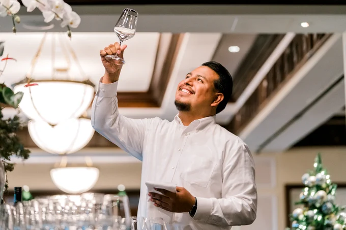 A professional server inspects a wine glass with a smile at the Fairview Dining Room in Durham, NC