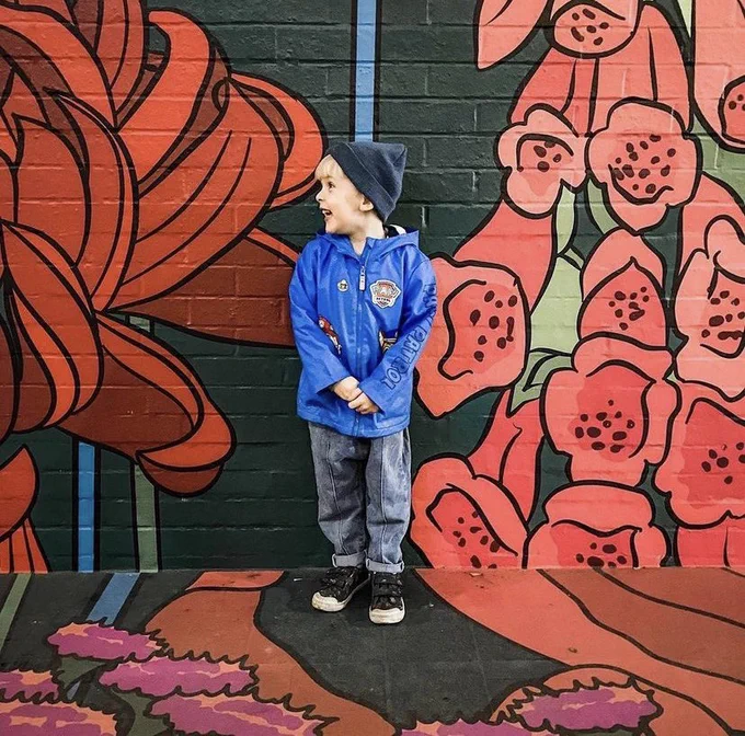 Small boy standing next to the Graphic Rewilding Artwork by Baker & Borowski