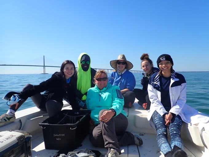Photo of the full crew from February's sawfish survey. They all sit on the bow of the boat with the Skyway bridge in the background