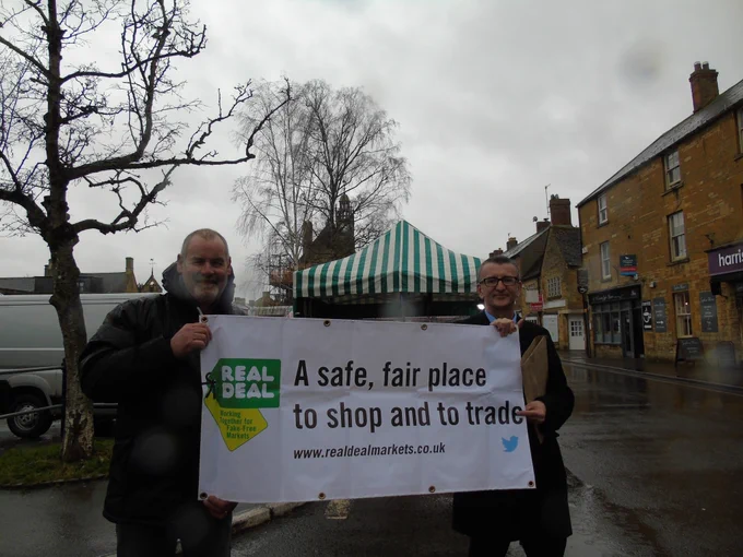 Dave Joynes, MD of Cotswold Markets, and Jason Poole, Trading Standards manager, holding a banner showing support for the Real Deal scheme

