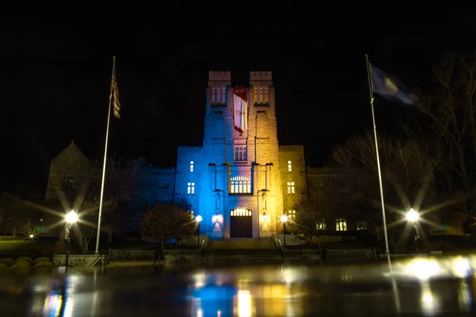 Burruss Hall is illuminated with blue and yellow lights in the evening