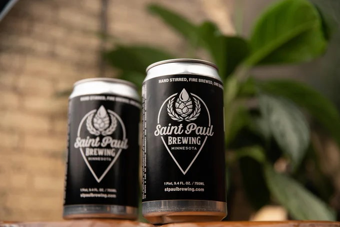 two canned beers, plants, brick wall