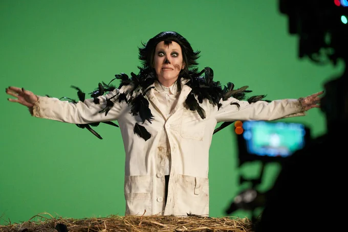 Catherine O'Hara in Schitt's Creek. She is standing in a giant bird's nest, dressed as a scientist, covered in black crow feathers.