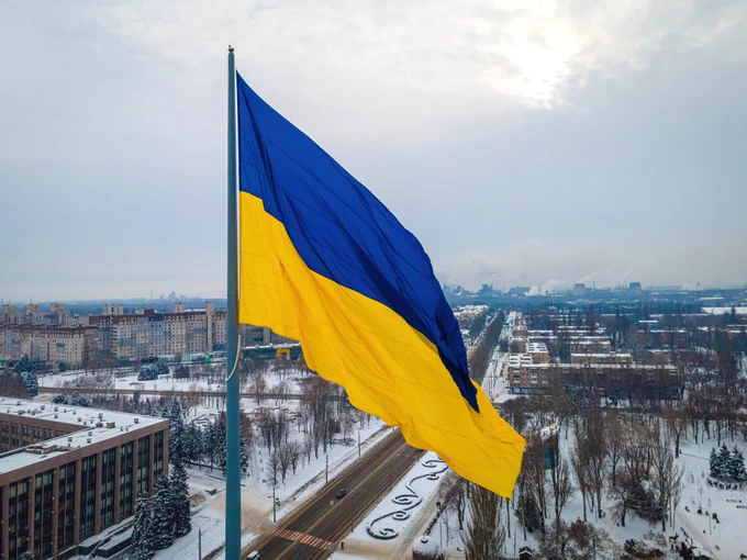 The blue and yellow Ukrainian flag against the backdrop of a snow-covered city. 