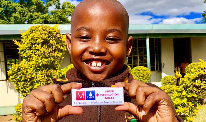 Child holding a MadiDrop  water purification tablet