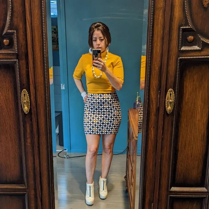 Dr. Beal, high femme, in a selfie wearing a mustard top and geometric mini skirt.