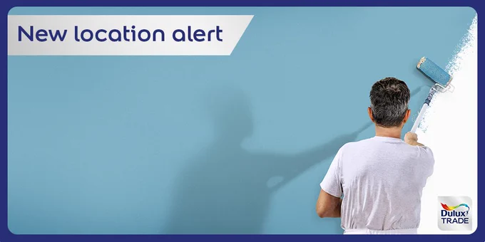 Decorator painting a wall with new location alert banner