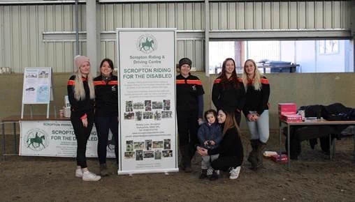 Equine students at Broomfield Hall stood by a banner for Scropton Riding for the Disabled.