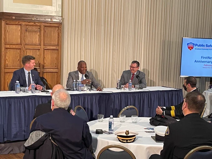 Ed Parkinson, Steve Benjamin, and Rich Carrizzo seated behind table speak into microphones; public safety officials seated at tables listening