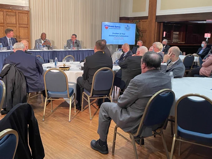Ed Parkinson, Steve Benjamin, and Rich Carrizzo seated behind table speak into microphones; public safety officials seated at tables listening