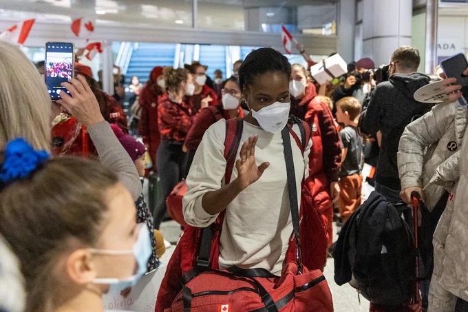 A Canadian athletes arrives at the airport and waves.