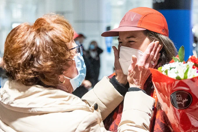 An older woman embraces a Canadian athlete by caressing her face.