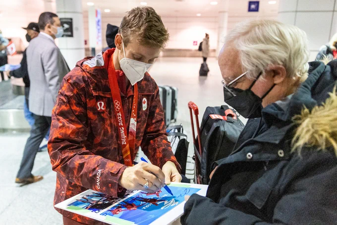 A Canadian athlete signs a fans picture.