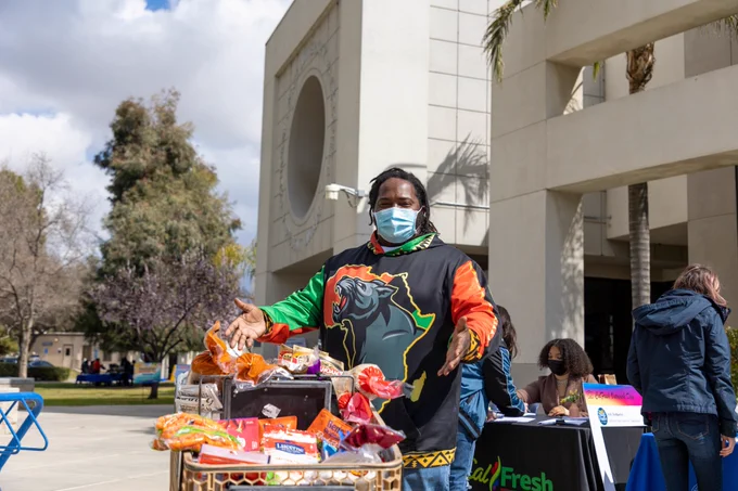 Student showing cart with groceries during CSUB CalFresh resource fair. 