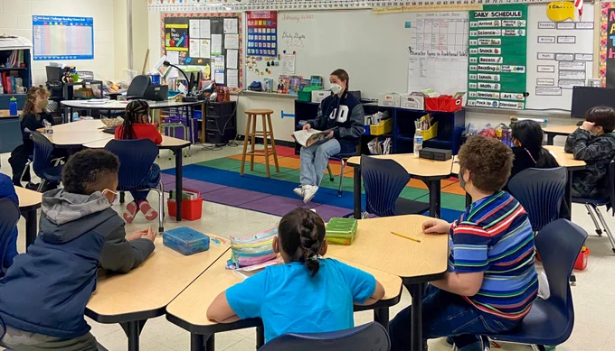 A Duke student-athlete reads to a classroom of elementary school students.