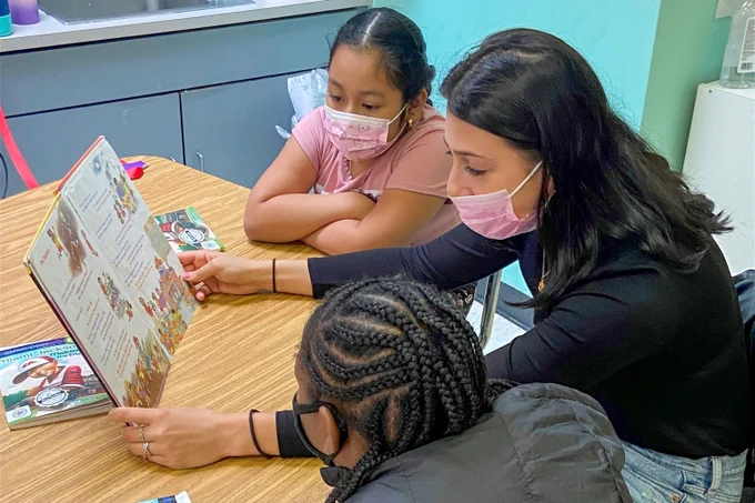 A Duke student-athlete reads to two elementary school students.